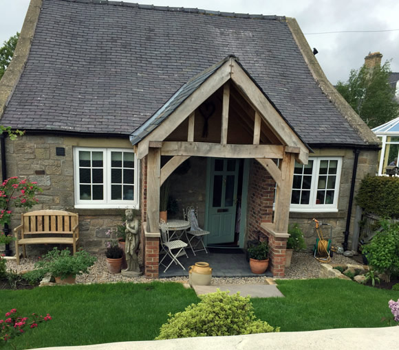 stone cottage with teal front door and green grass out front in garden