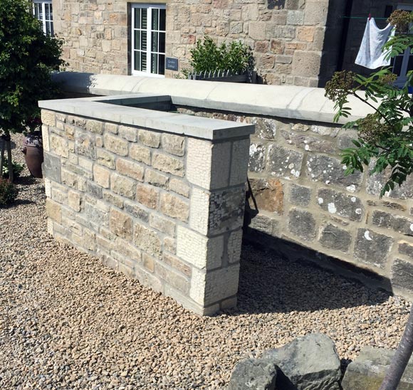 stoned garden wall surrounding house in matching stone build