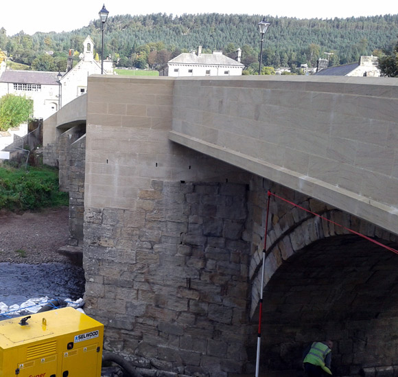 grade 2 listed bridge having restorative work completed underneath by person in high-vis 